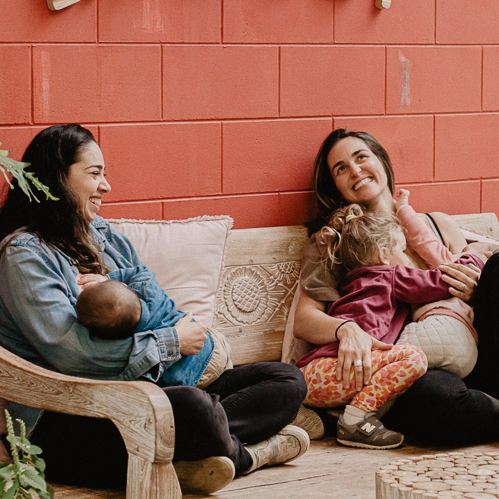 two women sitting together breastfeeding and smiling