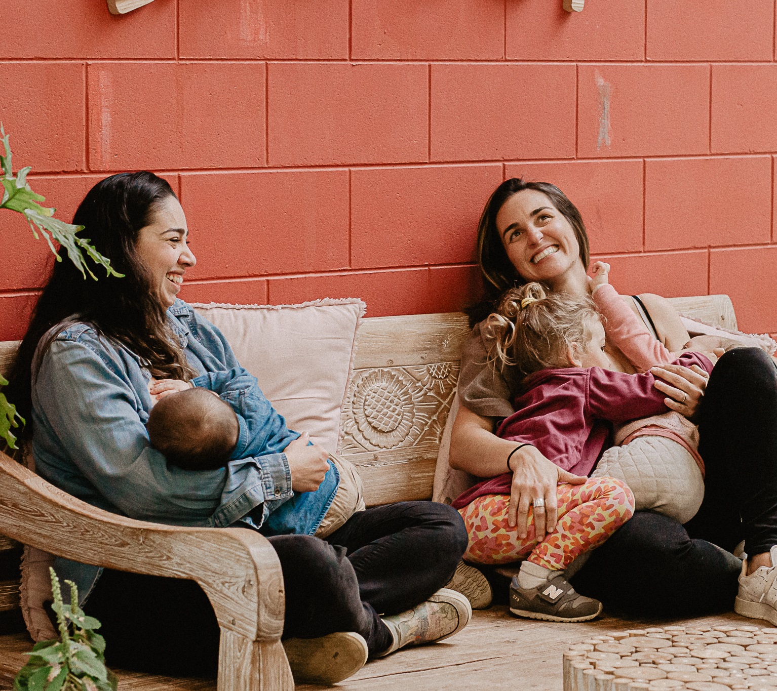 two women sitting together breastfeeding and smiling